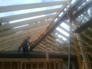 Rafters going up over a new addition with a worker on the wall in Collinsville