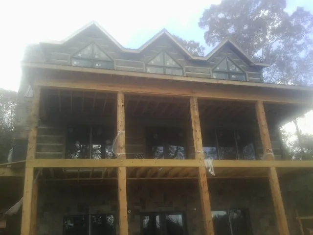 Dormers and porch framing on a large log home under construction — Roof Coating work by our crew in Collinsville