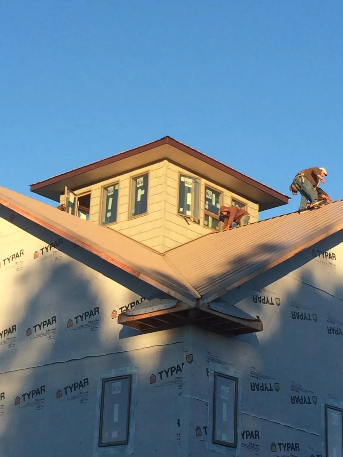 Roofers working around a rooftop cupola on a new metal roof at sunset — Roof Waterproofing in Collinsville by Roofing Brothers